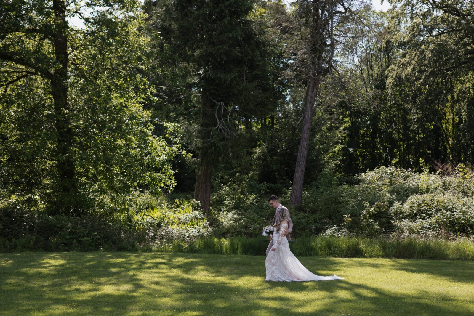 Bride walking through a sunlit woodland garden