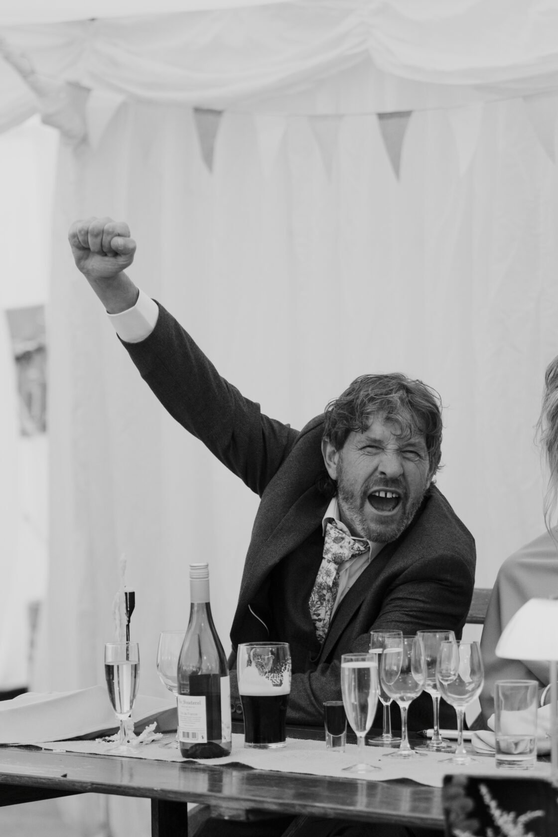 Best man cheering during a lively wedding speech in black and white