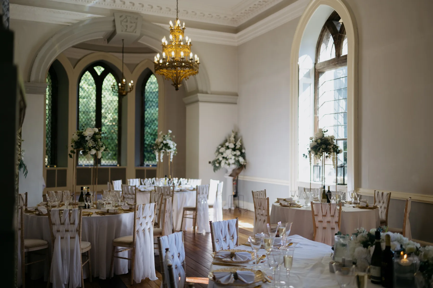 Wedding breakfast tables and floral arrangements in the ballroom at Clearwell Castle