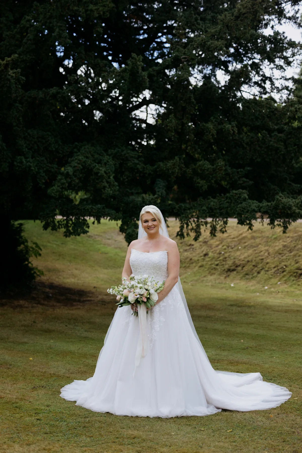 Bride holding a pale flower bouquet in the grounds of Clearwell Castle