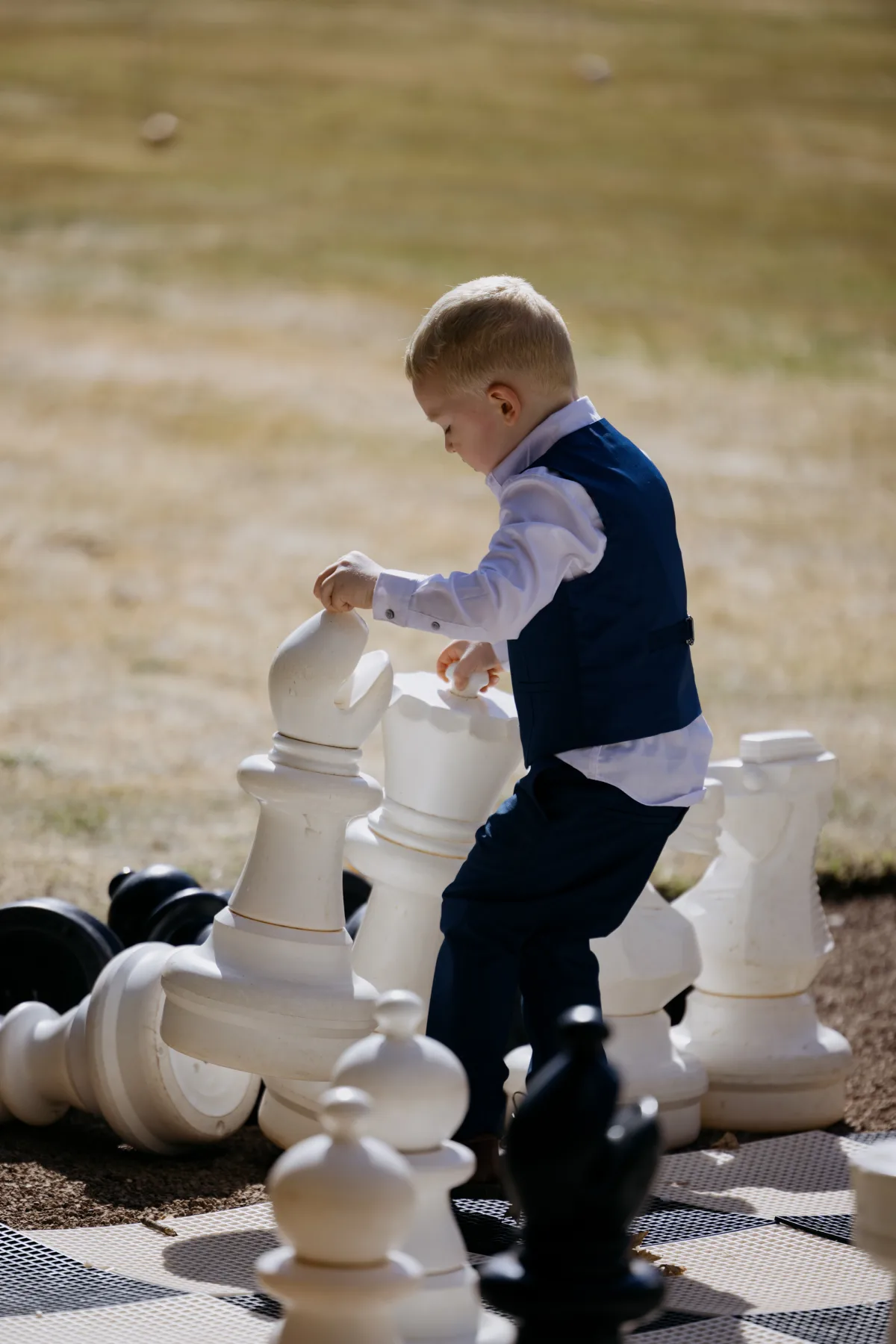 Young wedding guest moving a giant chess piece at Clearwell Castle