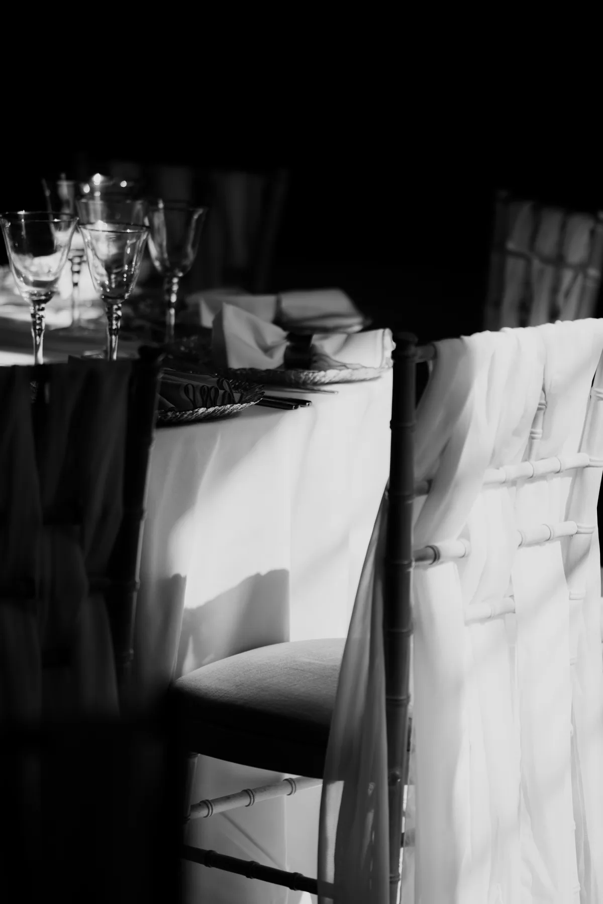 Black-and-white detail of a wedding breakfast table and dressed chair at Clearwell Castle