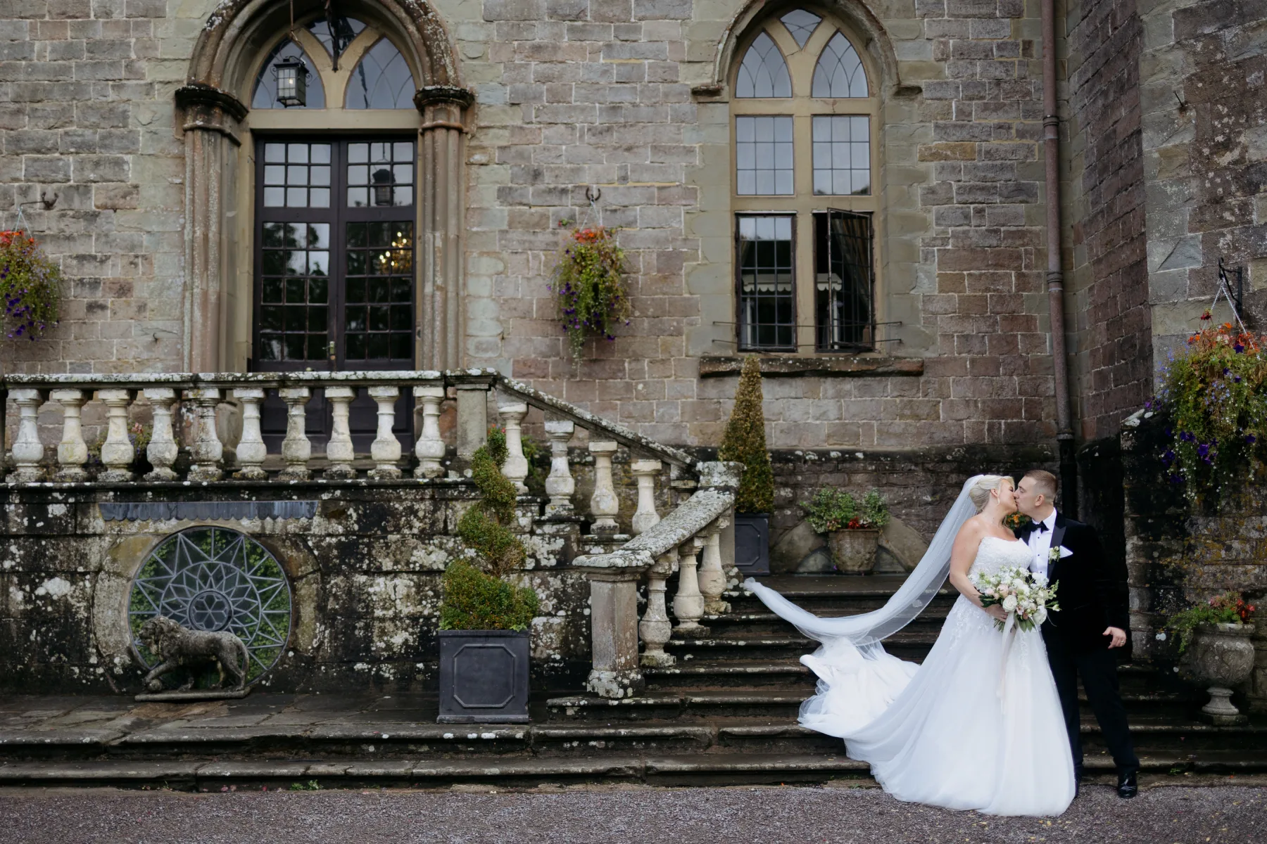 Newlyweds kissing on the historic steps outside Clearwell Castle in the Forest of Dean