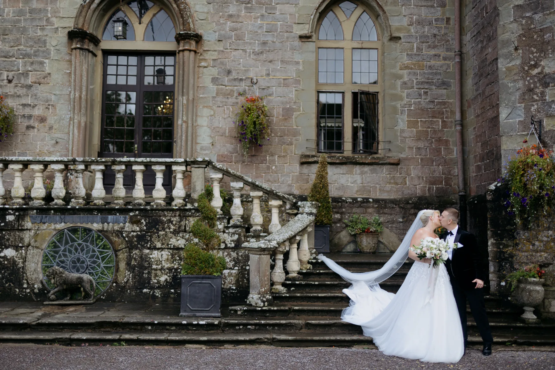 Emily and David kissing on the historic steps outside Clearwell Castle