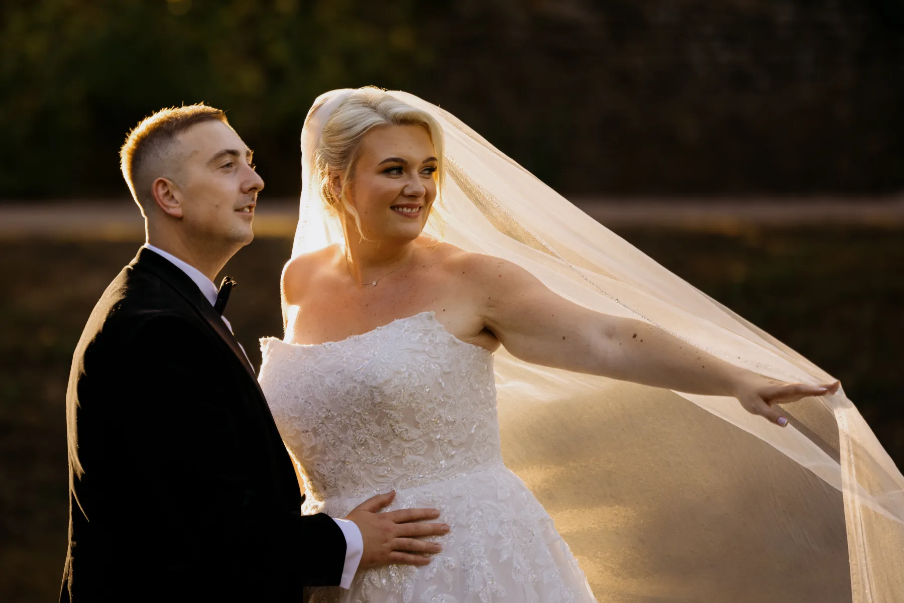 Wedding couple with a flowing veil at sunset