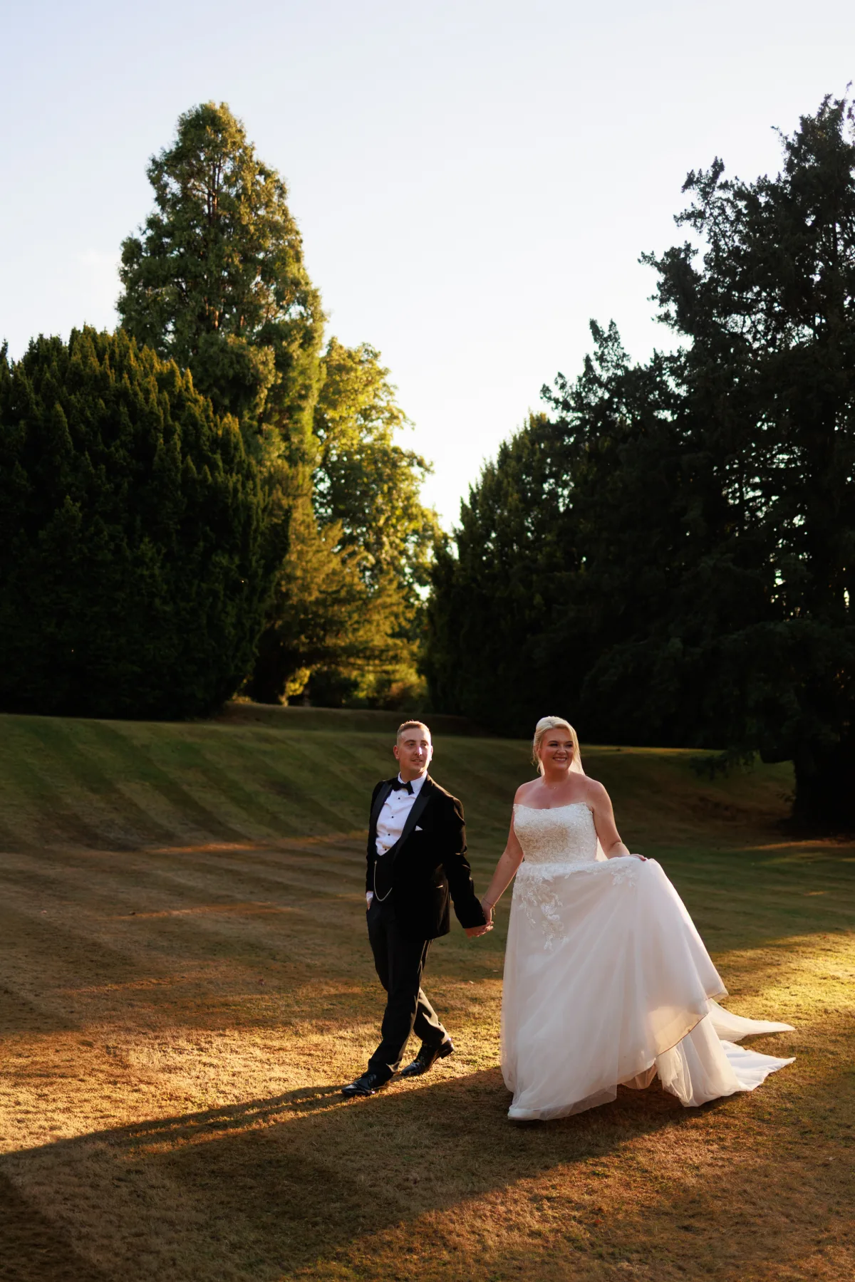 Emily and David walking together at sunset in the Clearwell Castle grounds