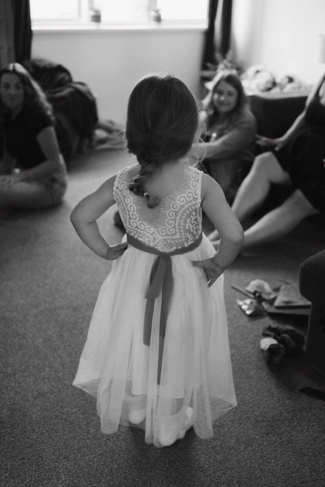 Flower girl waiting patiently during wedding preparations in black and white