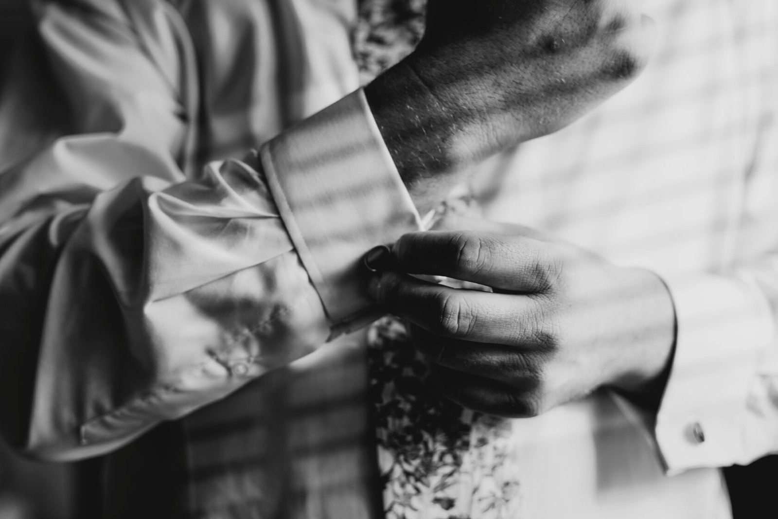 Groom fastening his cufflinks during wedding preparations