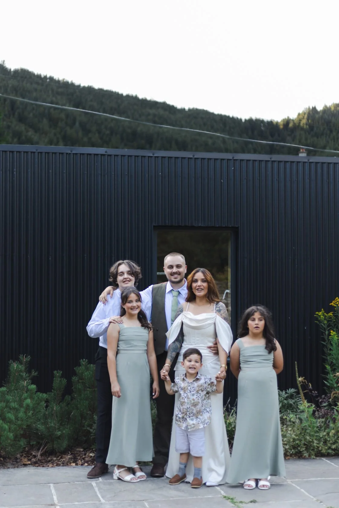 Family group posing together outside a modern black wedding venue