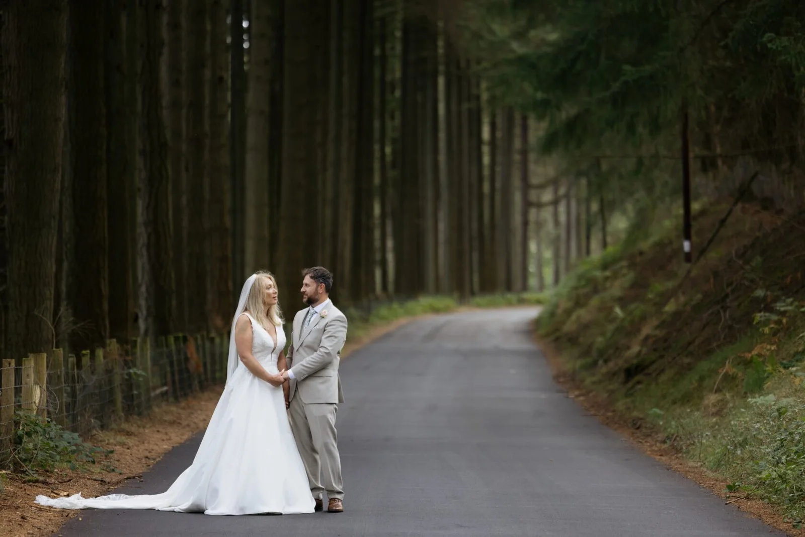 Newlyweds sharing a quiet moment on a forest road in Mid Wales