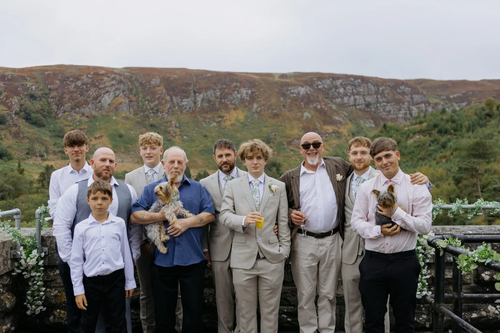Wedding guests and two small dogs posing against the Elan Valley hills