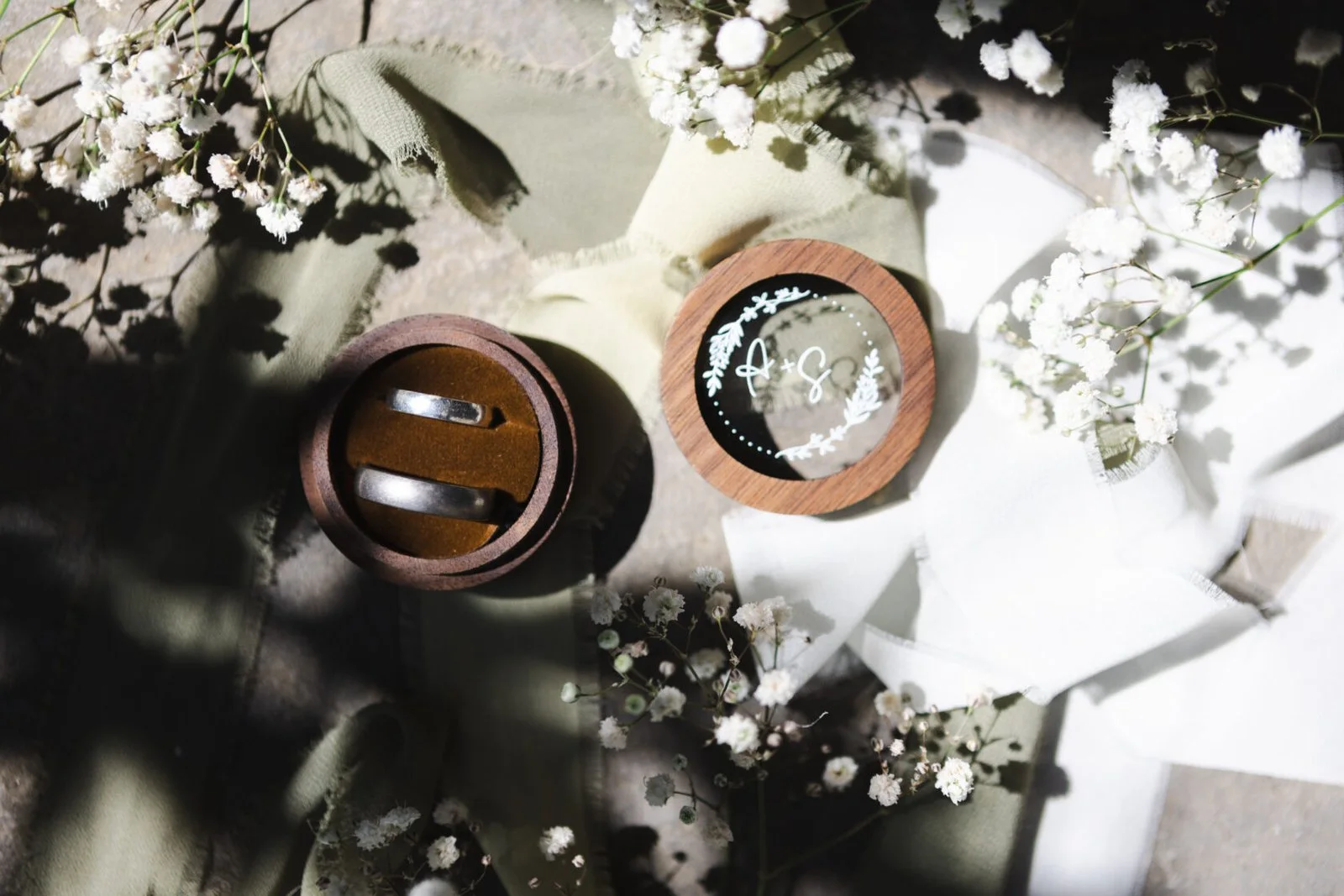 Wedding rings arranged with flowers in dappled sunlight