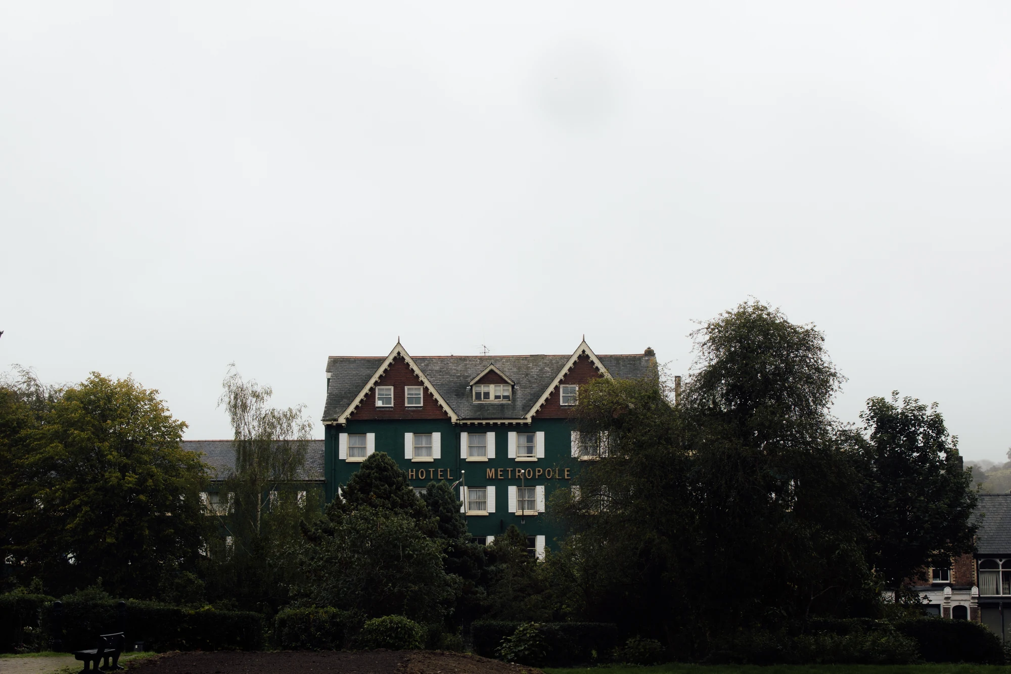 The green exterior of the Metropole Hotel seen beyond trees in Llandrindod Wells