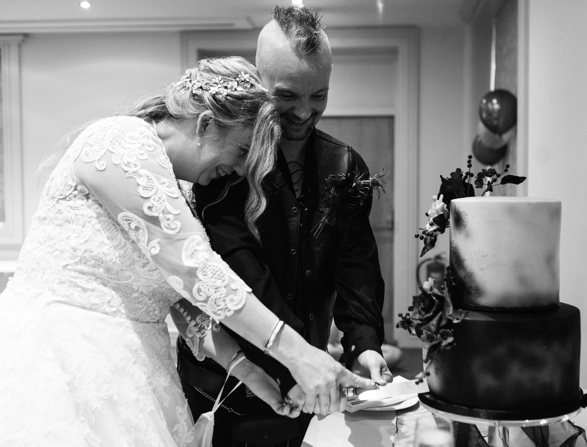 Ruth and David laughing as they cut their two-tier wedding cake