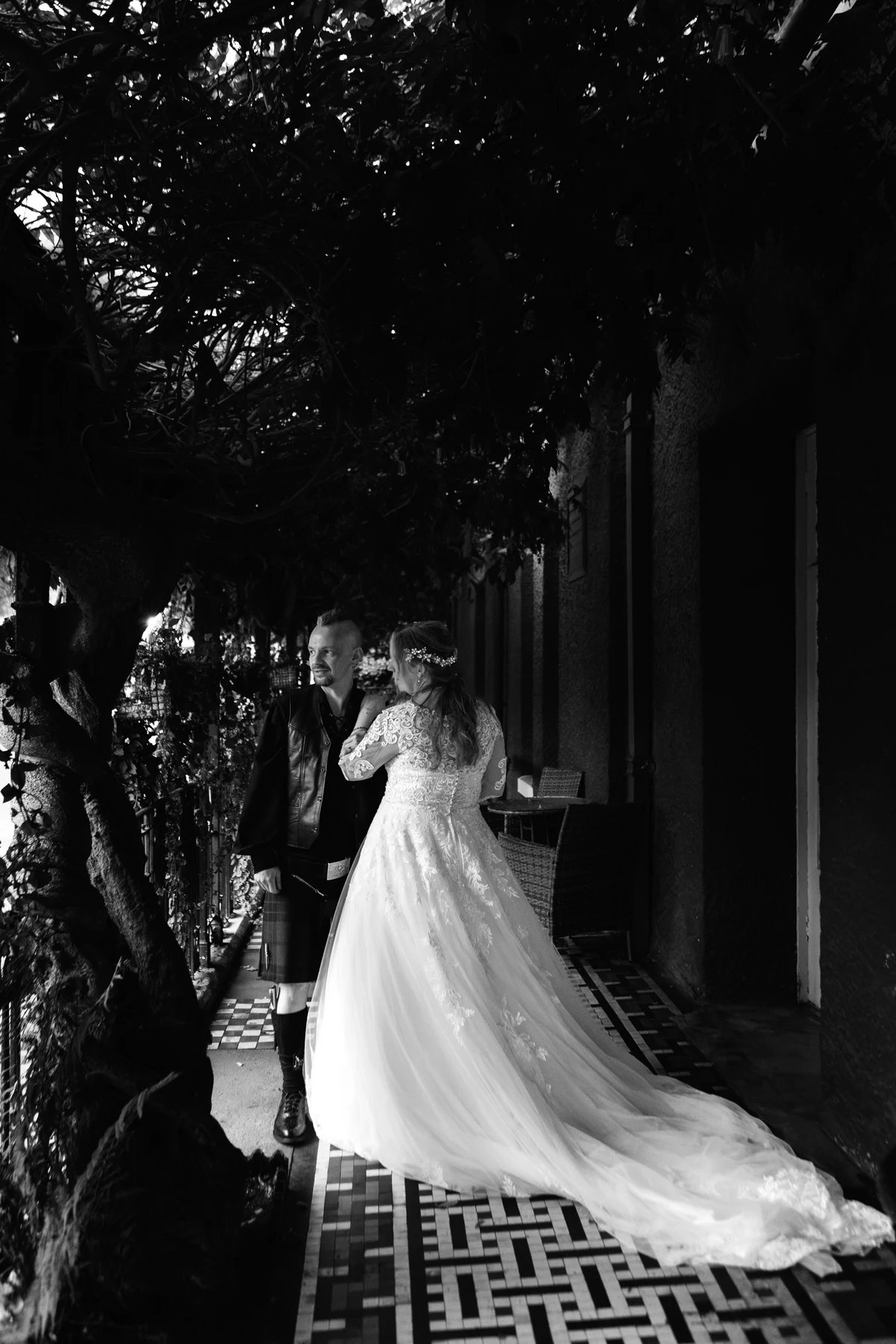 Black-and-white portrait of Ruth and David with her dress train spread across the tiled terrace