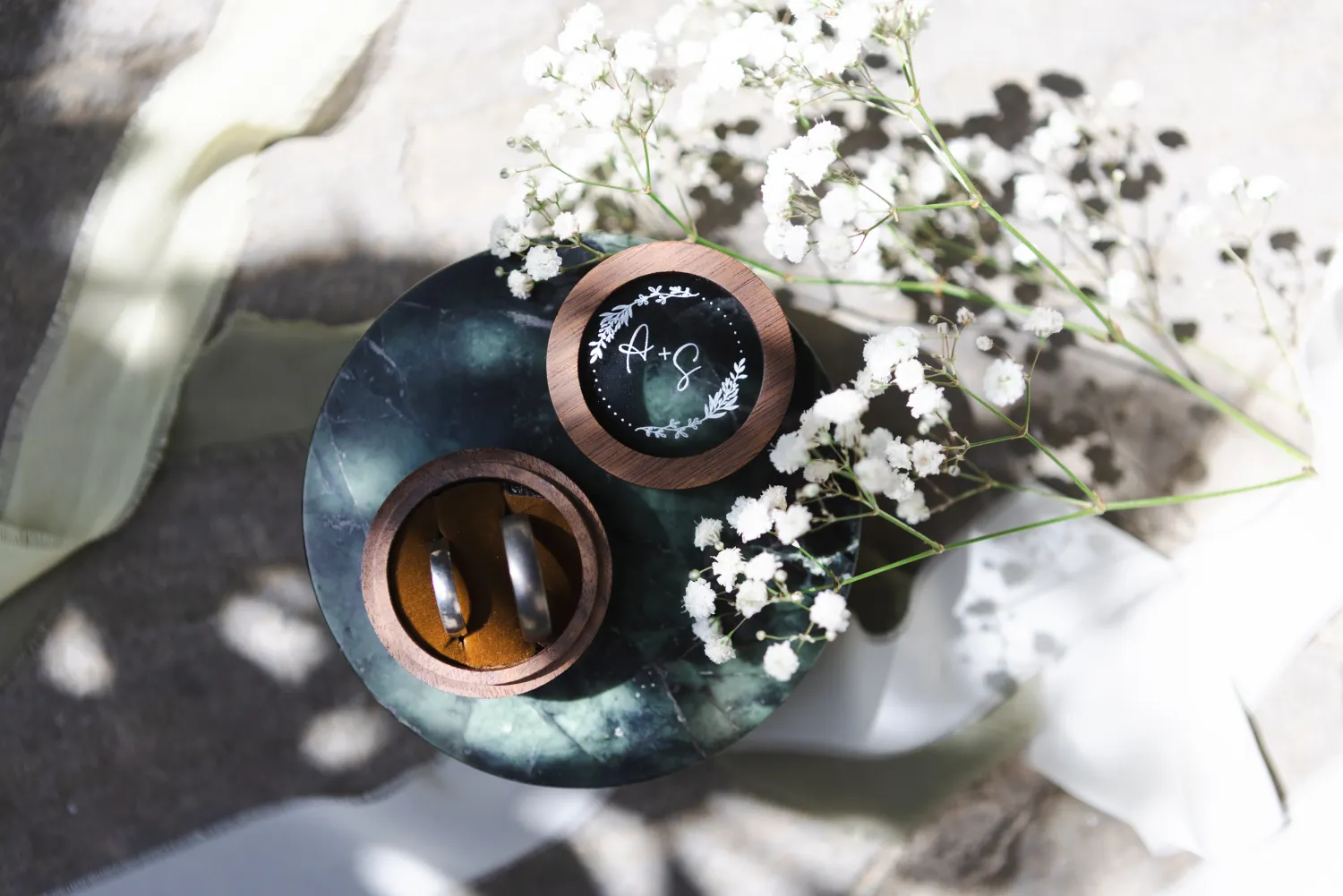 Autumn and Sebastian's wedding rings in wooden boxes among white flowers