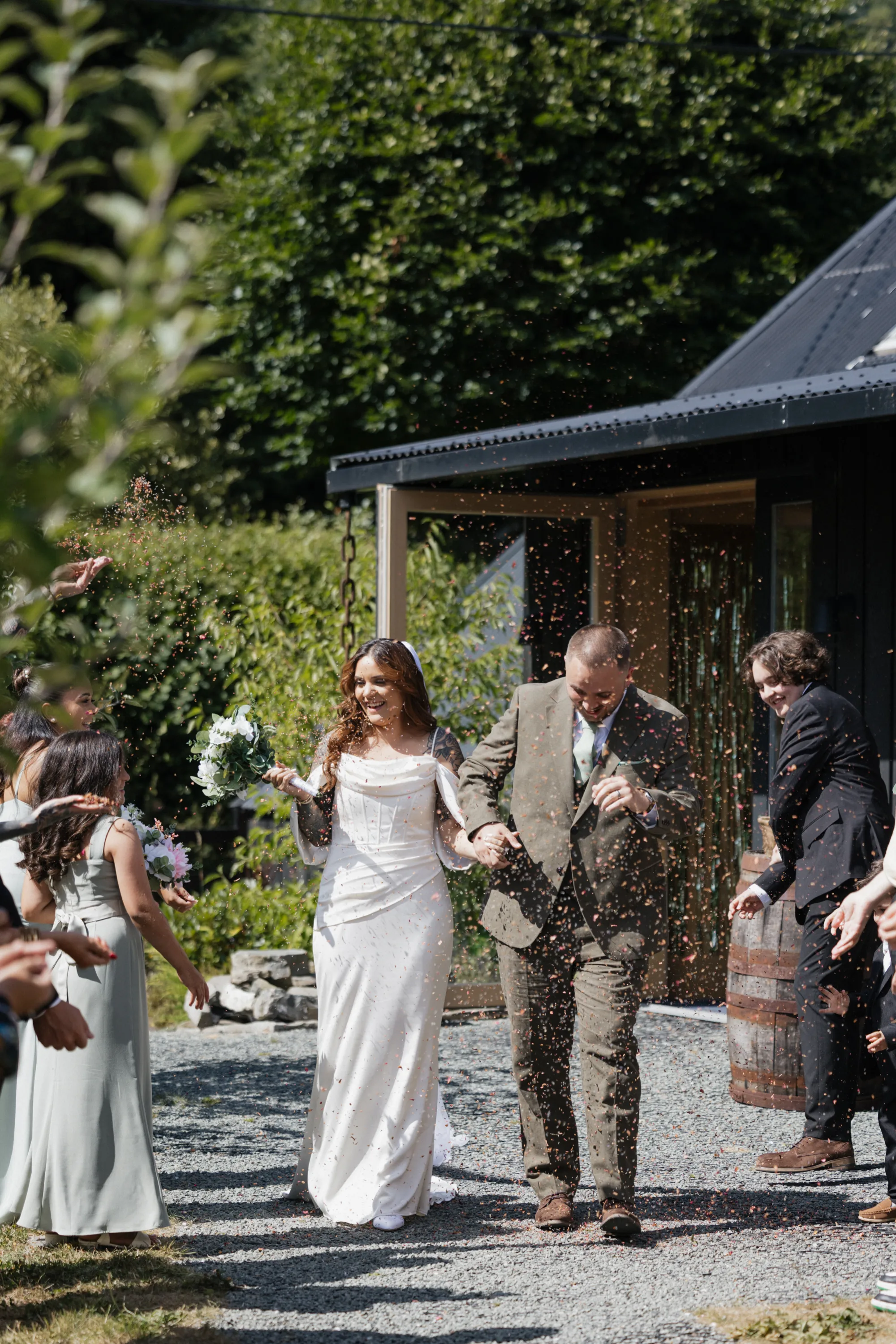 Autumn and Sebastian walking through confetti outside Nant y Walch Barn near Llanwrtyd Wells