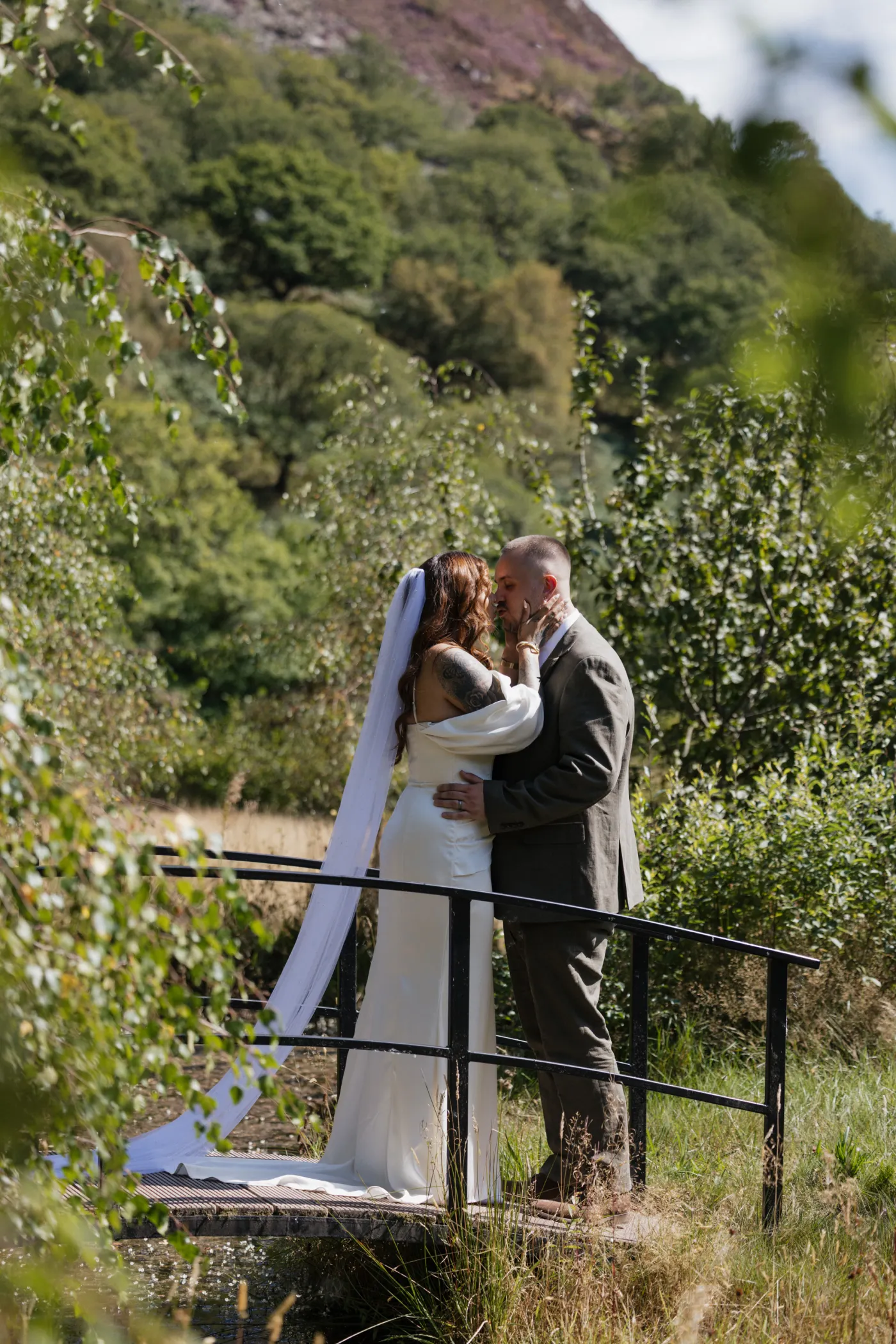 Newlyweds kissing among trees in the Irfon Valley near Llanwrtyd Wells