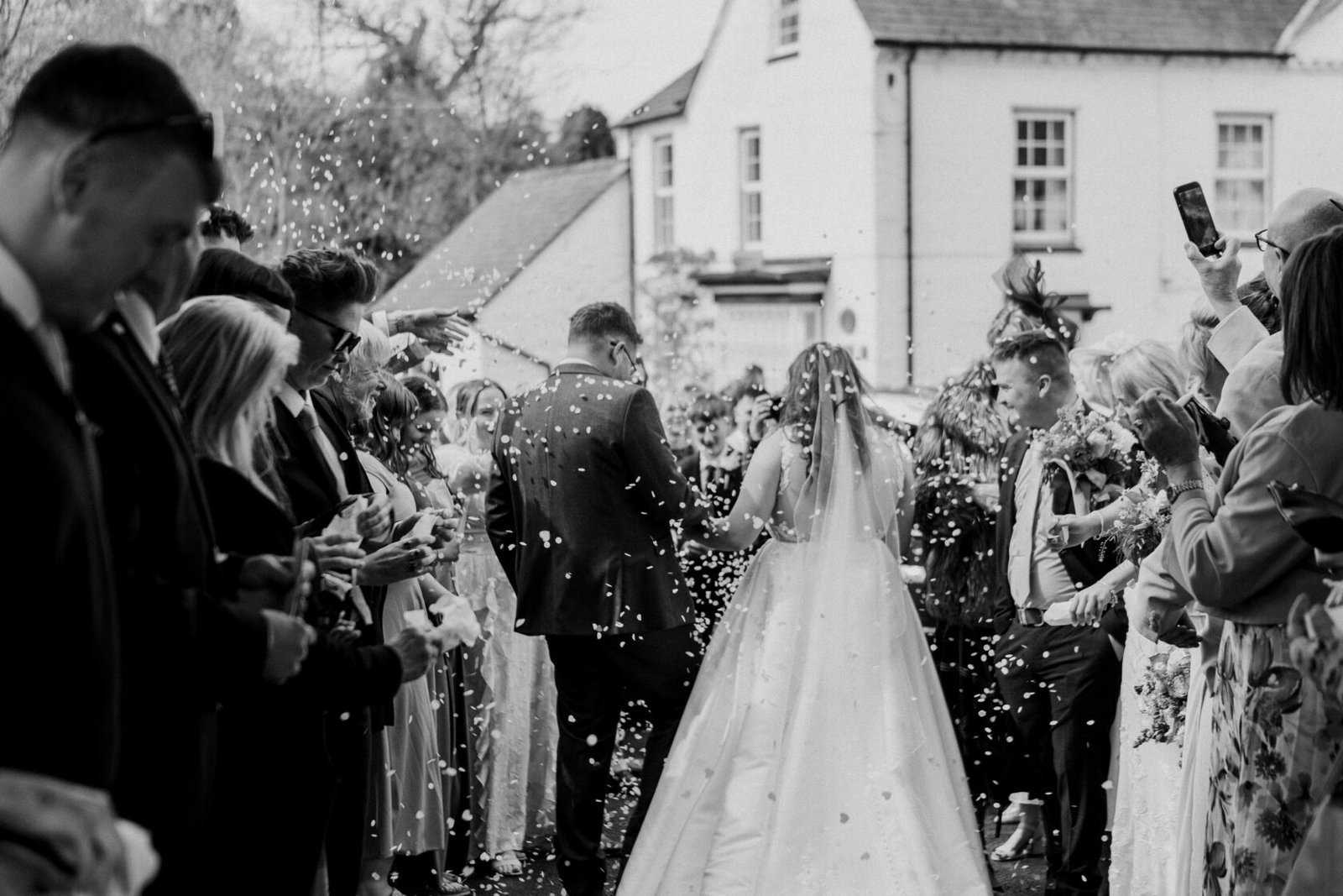 Guests celebrating a joyful confetti exit in black and white