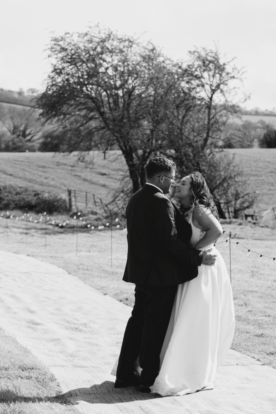Newlyweds kissing in the countryside in black and white