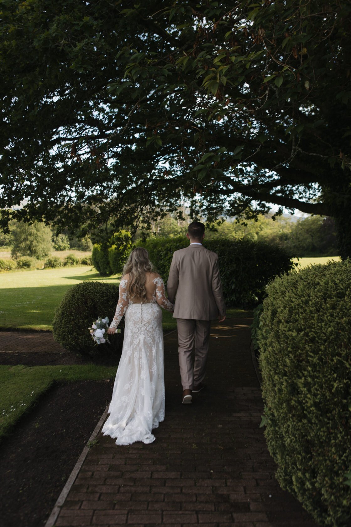 Newlyweds walking away together along a garden path