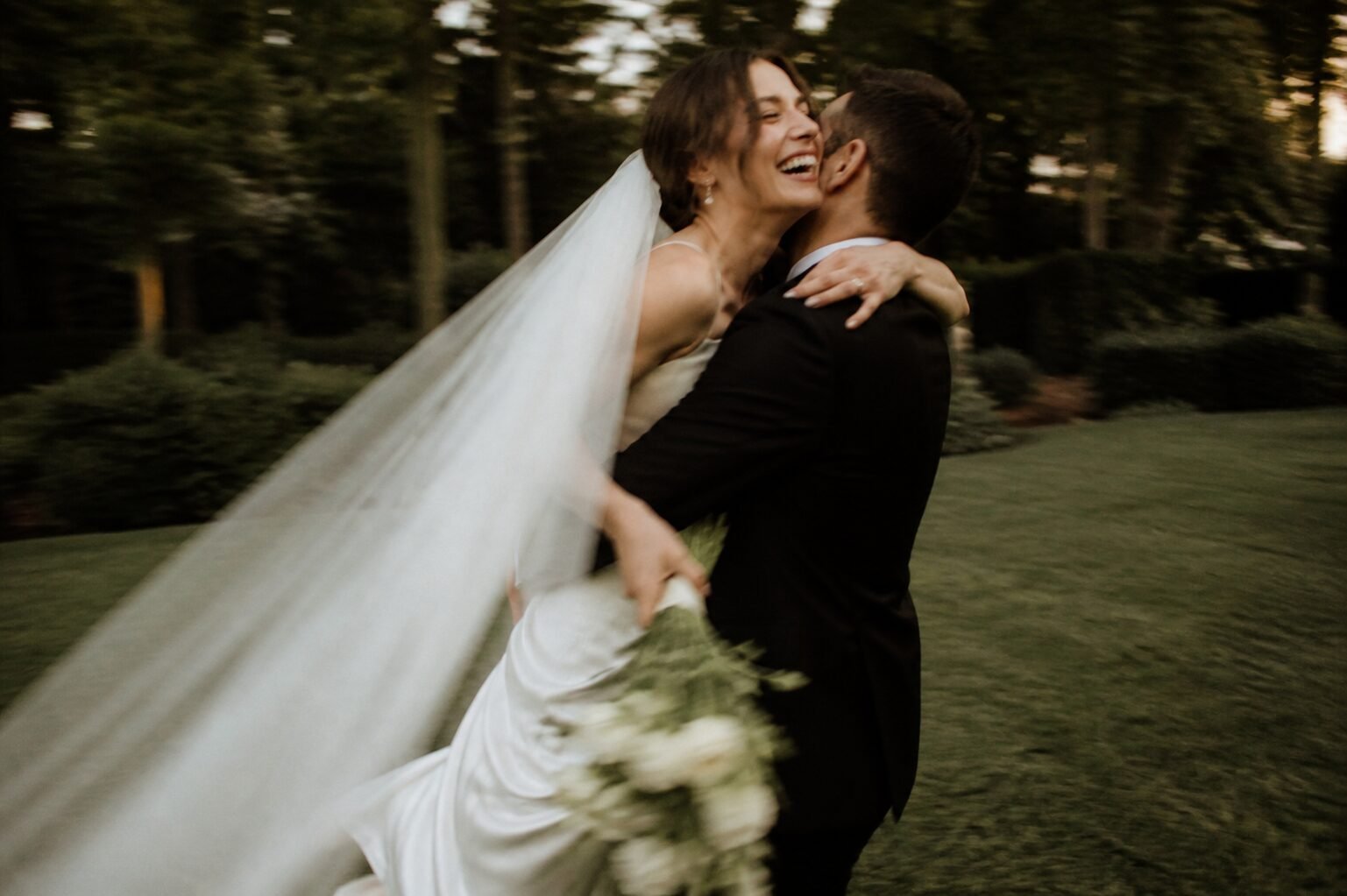 Newlyweds spinning and laughing in a woodland garden