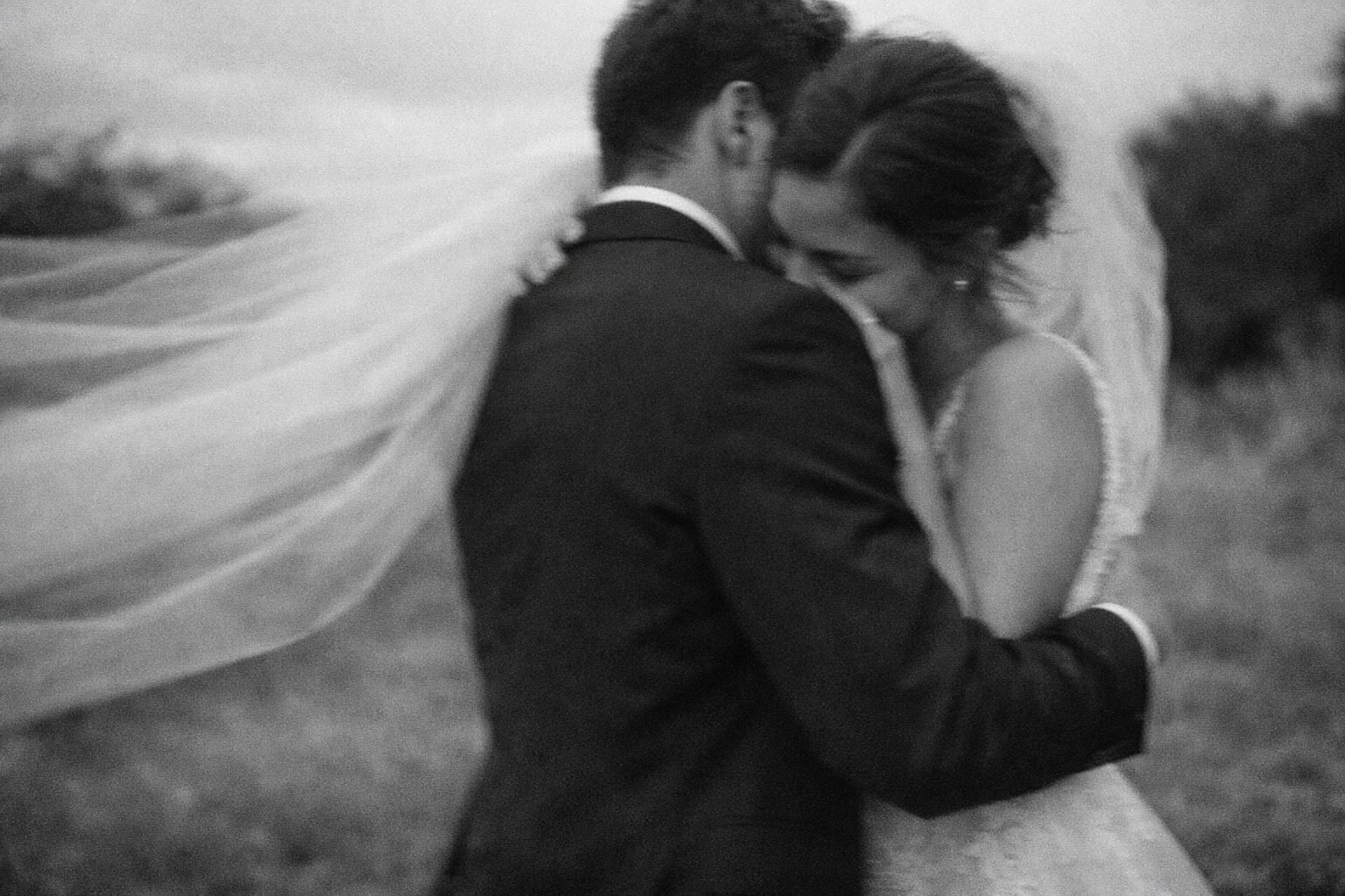 Newlyweds sharing a windswept portrait in black and white