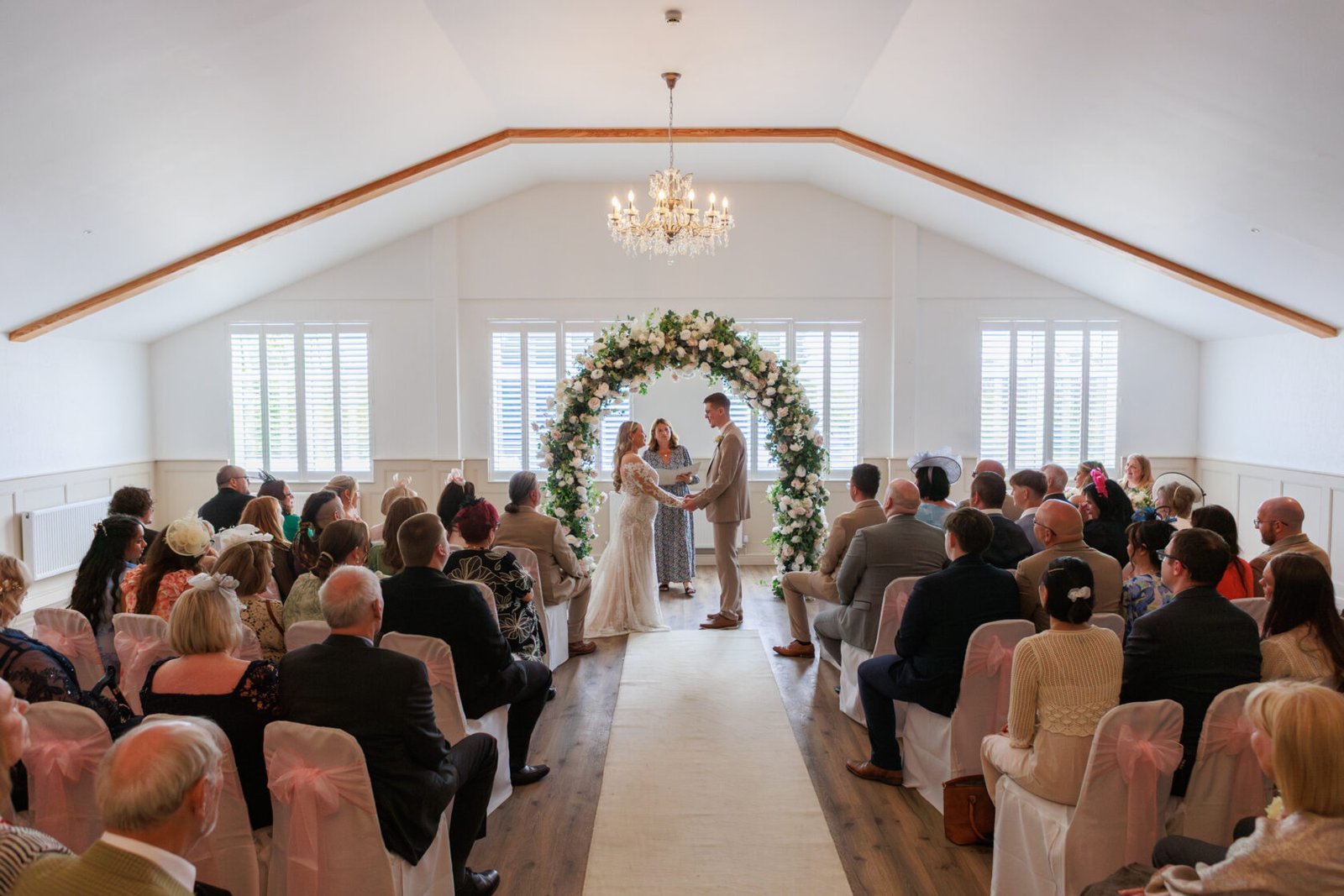 Wedding ceremony taking place in a bright, flower-filled room
